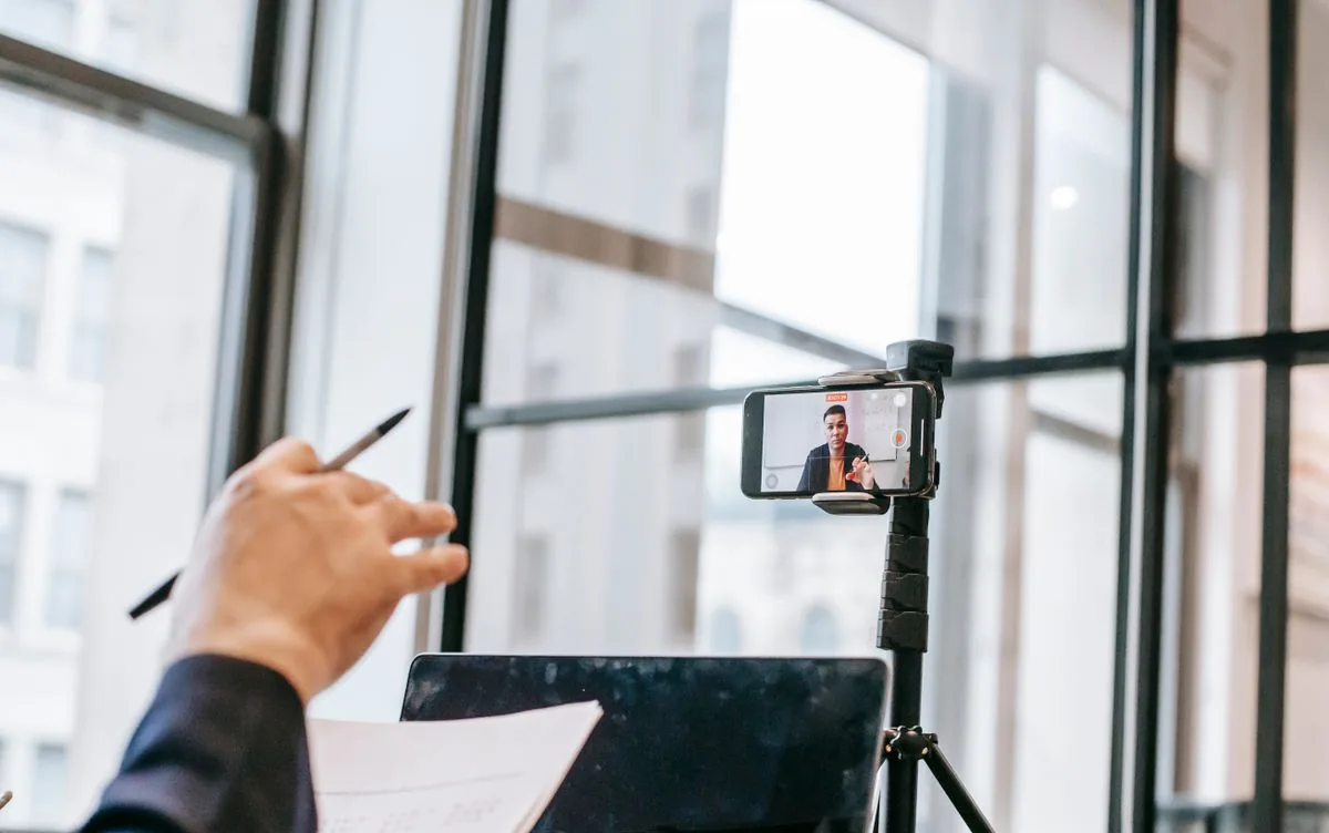 A course creator recording a lesson with a phone and notes.